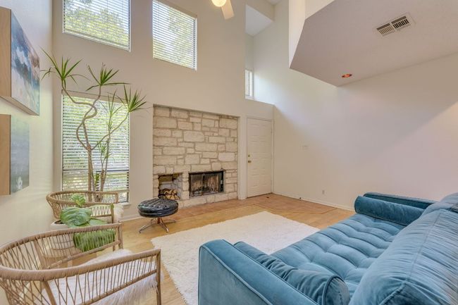 Living area featuring a high ceiling, plenty of natural light, a fireplace, ceiling fan, and wood finished floors | Image 5