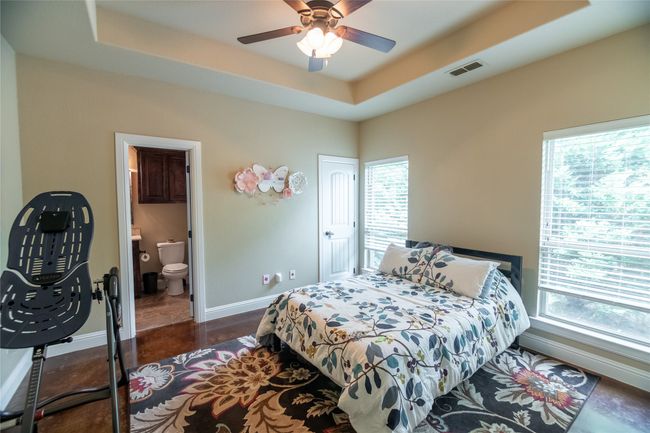 Bedroom featuring multiple windows, baseboards, a raised ceiling, and ensuite bath | Image 26