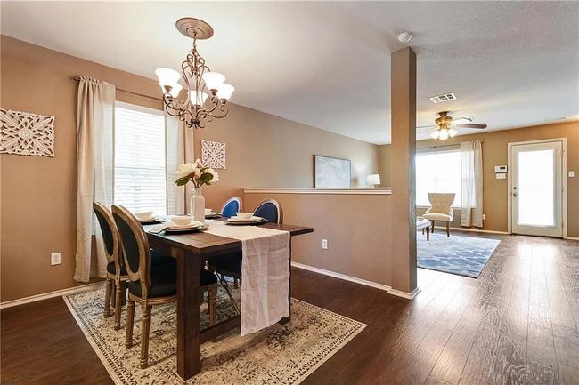 Dining room featuring dark wood-style flooring, a chandelier, baseboards, and ceiling fan | Image 8