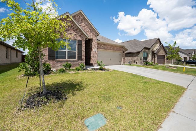 View of front facade with brick siding, concrete driveway, a garage, and a front yard | Image 4