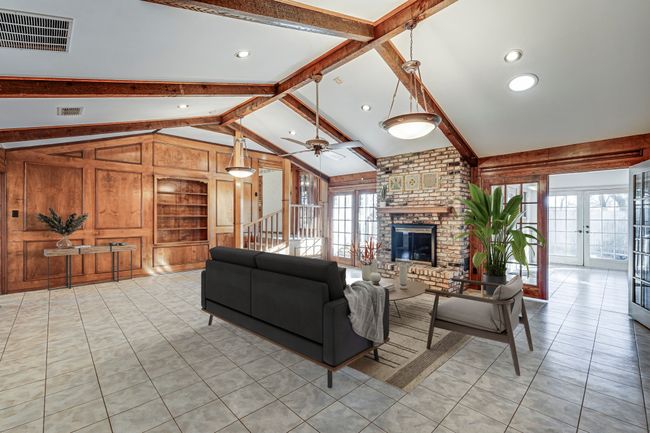 Large family room, featuring cathedral ceiling, gas log fireplace, french doors to outside, steps leading up to the kitchen, and another doorway leading to the sunroom. | Image 11