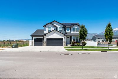 View of front facade with a front yard, a mountain view, a garage, and solar panels | Image 1