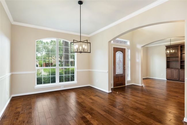 Showcasing timeless details, this front room has a magnificent chandelier and wide window all placed beneath an arched opening to the area. | Image 7