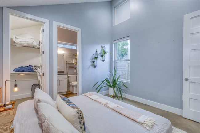 Bedroom with baseboards, a high ceiling, ensuite bathroom, and concrete floors | Image 12