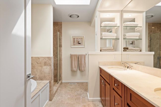 Full bath featuring a shower stall, double vanity, a skylight, and a garden tub | Image 11