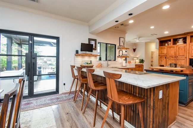 Another view of the dining room highlighting the large breakfast bar and French Doors, providing a peak out to the covered outdoor porch. | Image 12