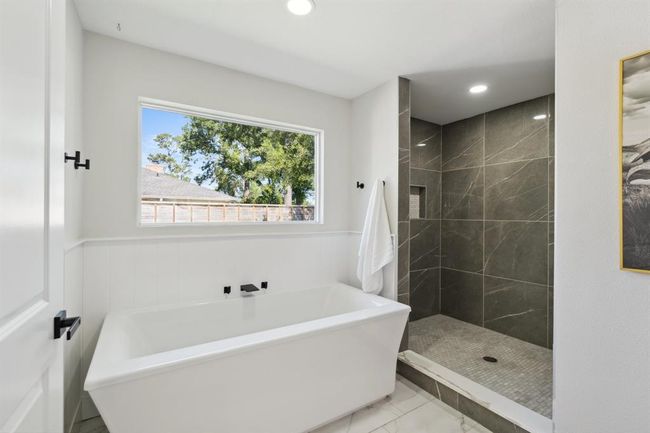 The soaking tub, framed by a sun-filled window, creates a spa-like moment of calm and comfort. | Image 20