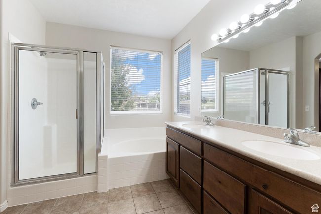 Primary bathroom with a shower stall, double vanity, a bath, and tile patterned flooring | Image 20