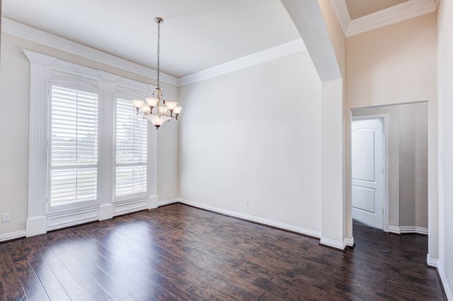 Empty room with ornamental molding, dark hardwood / wood-style floors, and a notable chandelier | Image 6