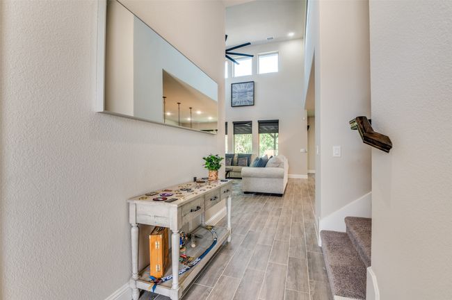 Hallway featuring healthy amount of natural light, wood finish floors, stairway, a towering ceiling, and a textured wall | Image 4