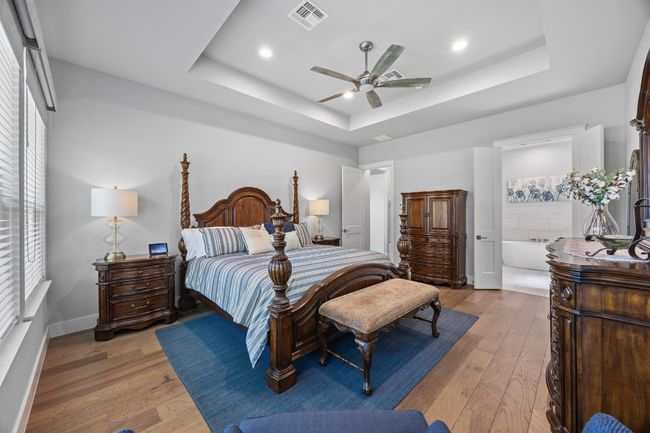 Private primary suite showcasing a beautiful trayed ceiling. This suite is conveniently located on the opposite side of the home from the other bedrooms, ensuring a sense of privacy. | Image 21