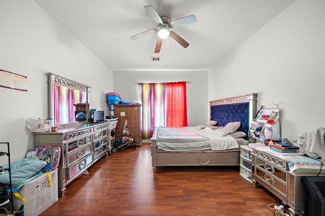 Designed for both rest and relaxation, the primary bedroom features tall ceilings, a ceiling fan, and generous square footage that easily accommodates a king-size bed and more. The neutral wall color and warm flooring create a calming atmosphere, while the ensuite bath adds convenience and comfort just steps away. | Image 14