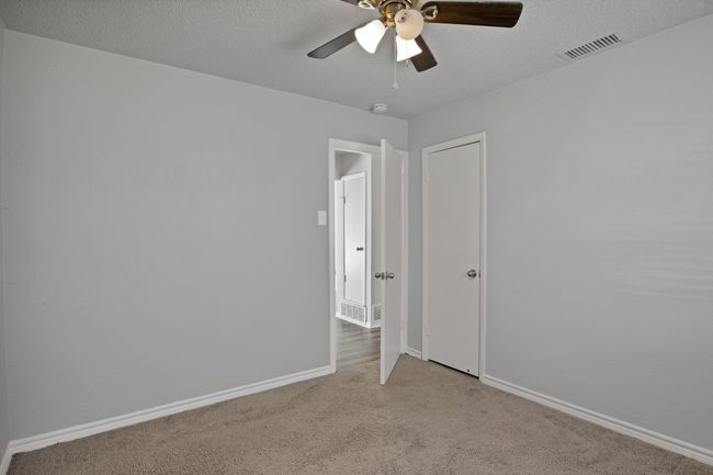 Carpeted spare room featuring visible vents, baseboards, a textured ceiling, and a ceiling fan | Image 19
