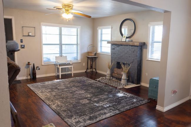 Living area featuring a ceiling fan, wood finished floors, and a brick fireplace | Image 4