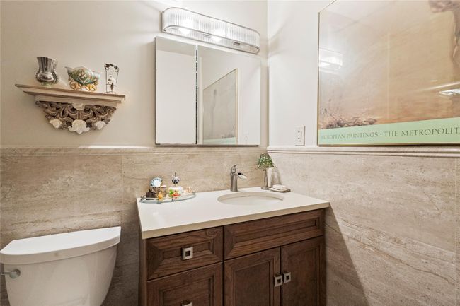 Half bath featuring vanity, tile walls, toilet, and a wainscoted wall | Image 20