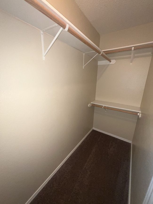 Walk in closet featuring dark carpet | Image 7