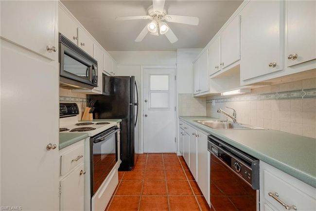 Kitchen featuring sink, black appliances, tasteful backsplash, and light tile flooring | Image 15