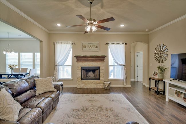Living area featuring a stone fireplace, recessed lighting, arched walkways, and ceiling fan with notable chandelier | Image 8