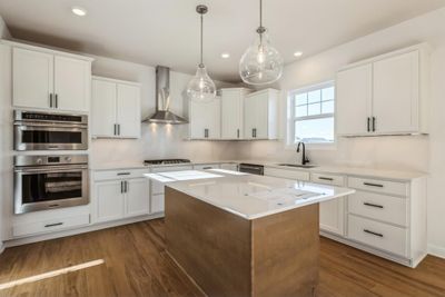 Photo is of the actual home. The stunning gourmet kitchen features a large center island, quartz countertops, LVP floors, stainless appliances and more! | Image 2