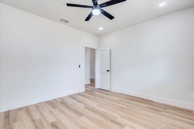 Empty room with ceiling fan, light wood finished floors, and recessed lighting | Image 25