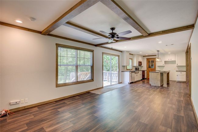 Unfurnished living room featuring dark wood-style flooring, beamed ceiling, a ceiling fan, and recessed lighting | Image 7