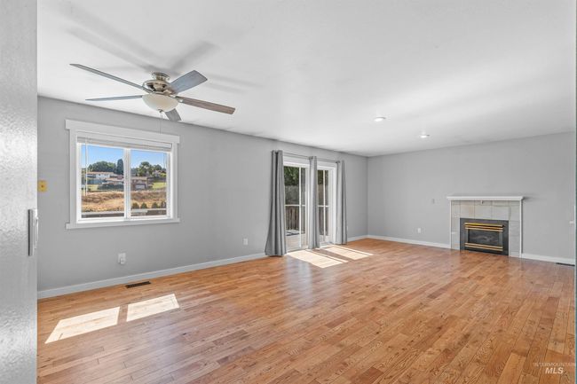Unfurnished living room featuring ceiling fan, light wood-style floors, and a fireplace | Image 8