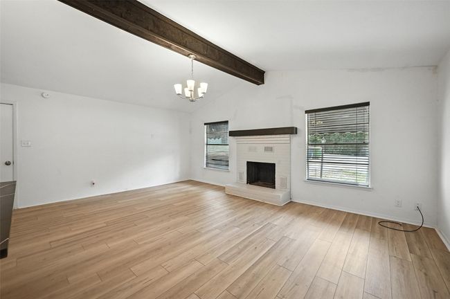 Unfurnished living room featuring a chandelier, light wood-style floors, and a fireplace | Image 7