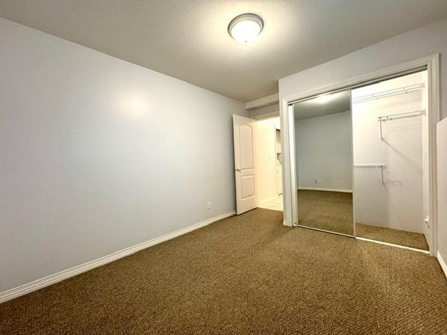 Unfurnished bedroom with dark colored carpet and a closet | Image 7