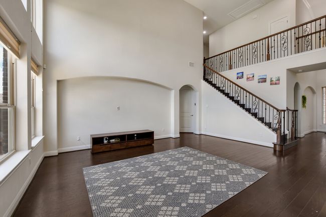 Living room featuring arched walkways, a towering ceiling, wood finished floors, and stairway | Image 16