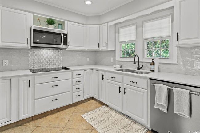 Kitchen with appliances with stainless steel finishes, a sink, light tile patterned floors, light countertops, and white cabinetry | Image 15