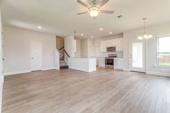 Unfurnished living room featuring ceiling fan with notable chandelier and light hardwood / wood-style floors | Image 8