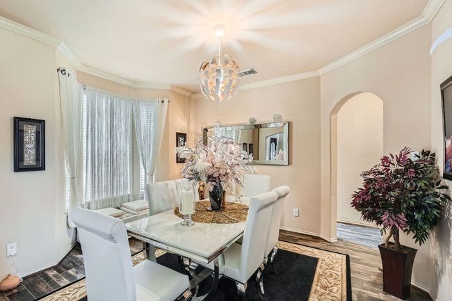 Dining area with a chandelier, crown molding, wood finished floors, and arched walkways | Image 10