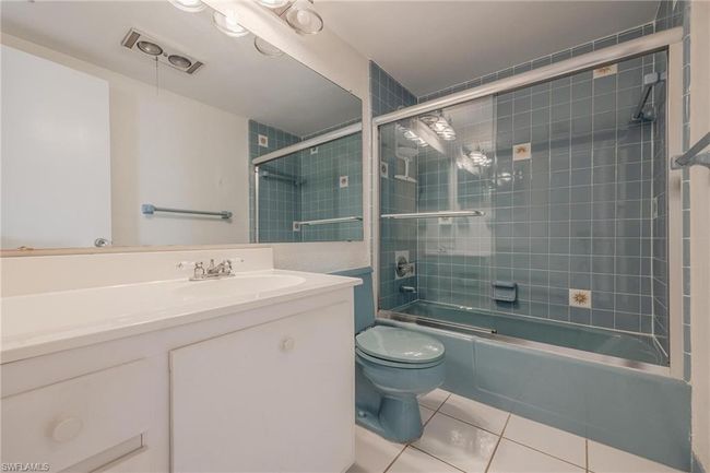 Full bathroom with tile floors, shower / bath combination with glass door, vanity, and toilet | Image 23