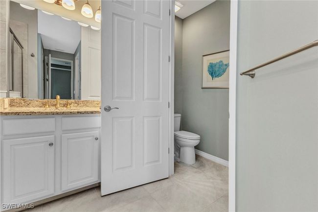 en suite Full bathroom featuring baseboards, toilet, an enclosed shower, double sink vanity, and tile patterned flooring | Image 36
