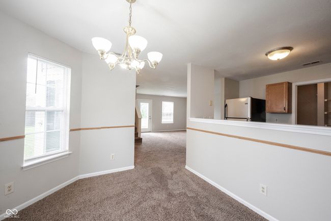 spare room featuring a chandelier, baseboards, visible vents, and light colored carpet | Image 13