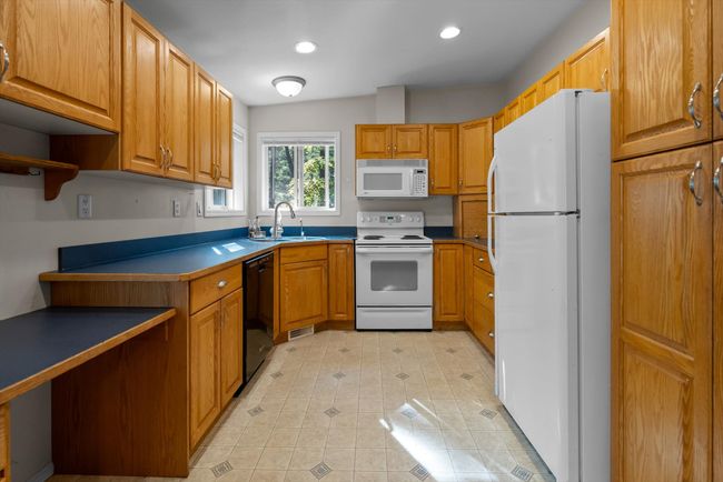 Kitchen featuring white appliances, recessed lighting, light and wood cabinetry | Image 13
