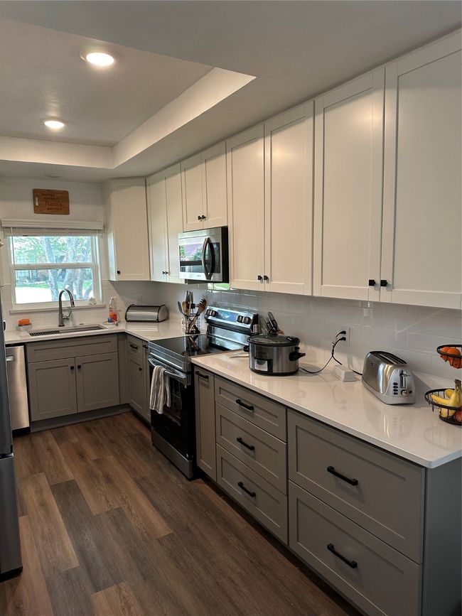 Kitchen featuring stove, a sink, gray cabinets, dark wood-style floors, and a raised ceiling | Image 7