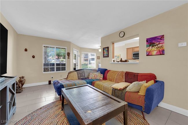 Living room with light tile patterned flooring, a ceiling fan, and baseboards | Image 5