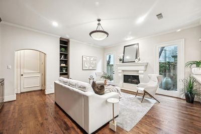 Living Room with Hardwood Floors, Crown Moulding, Arched Doorway, & a Cozy Fireplace | Image 3