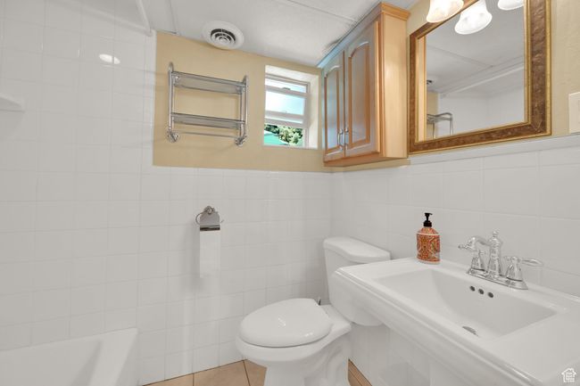 Bathroom with toilet, tile walls, a sink, and a bathtub | Image 21