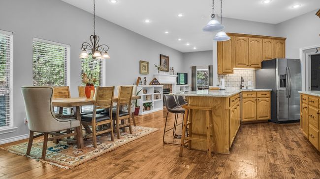 Kitchen featuring stainless steel fridge with ice dispenser, tasteful backsplash, an inviting chandelier, light stone countertops, and wood finished floors | Image 7