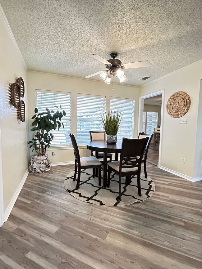 Dining area with ceiling fan, a textured ceiling, wood finished floors, and crown molding | Image 16