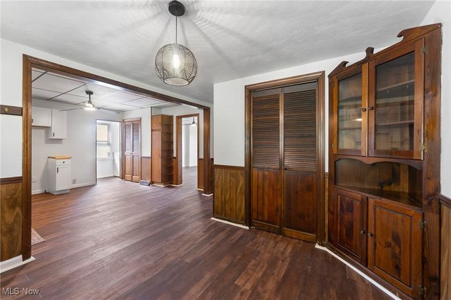 Unfurnished dining area with dark wood finished floors, ceiling fan, and wainscoting | Image 7