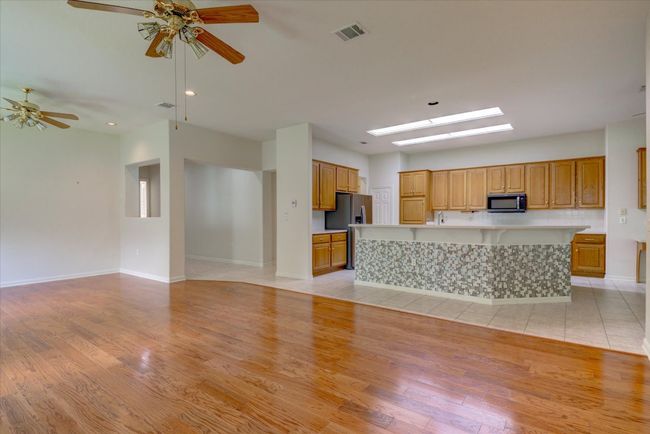 Unfurnished living room with ceiling fan, light wood finished floors, a skylight, and recessed lighting | Image 9
