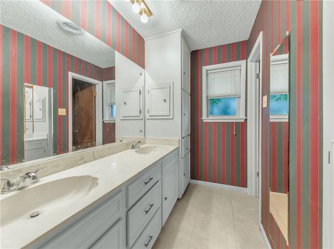 Bathroom with wallpapered walls, double vanity, a textured ceiling, and tile patterned flooring | Image 15