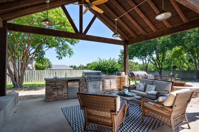 Fenced backyard with a ceiling fan, outdoor lounge area, a gazebo, and a patio | Image 24