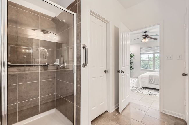 Ensuite bathroom with a stall shower, a ceiling fan, baseboards, and tile patterned flooring | Image 13