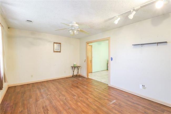 Spare room with wood finished floors, ceiling fan, a textured ceiling, rail lighting, and baseboards | Image 9