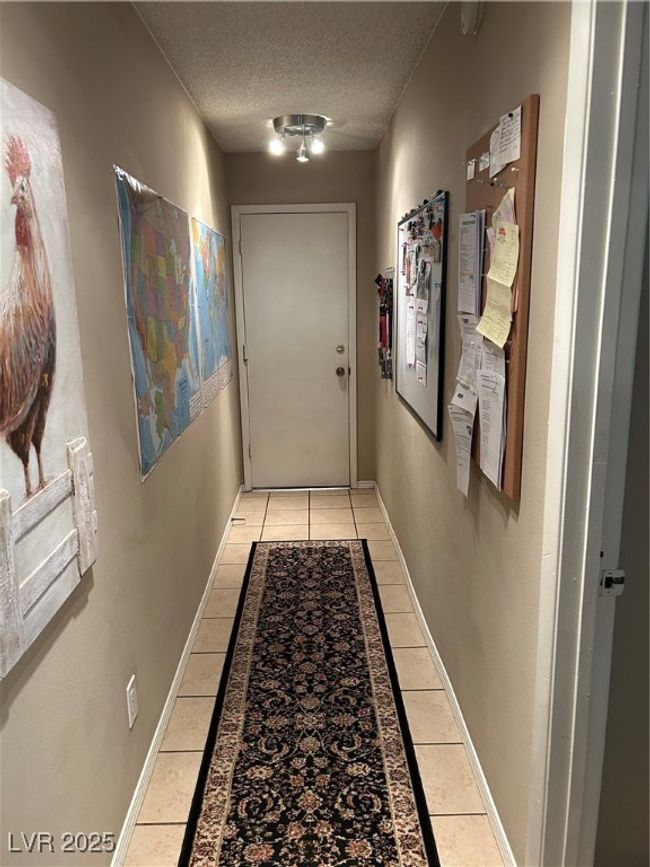 Hallway with light tile patterned floors and a textured ceiling | Image 38