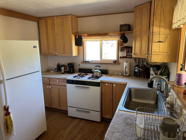 Kitchen with white appliances, light countertops, dark wood finished floors, and brown cabinets | Image 12
